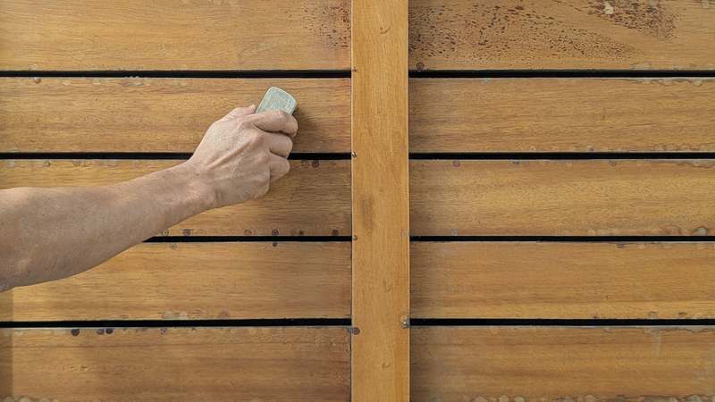 Close-up of hands sanding a smooth pine cutting board, with clamps and a hand plane visible nearby